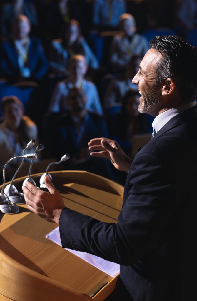 side-view-of-caucasian-businessman-standing-and-giving-presentation-in-the-auditorium.jpg